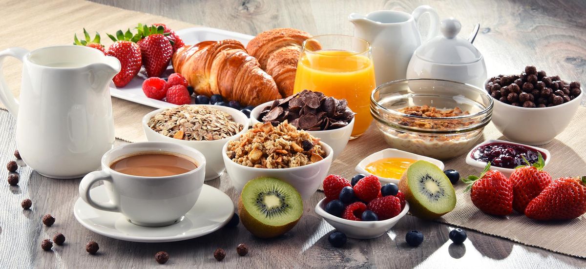 Een rijk gedekt ontbijt met croissants, fruit, muesli en jus d'orange